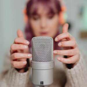 Close-up of a woman recording ASMR with a microphone indoors.