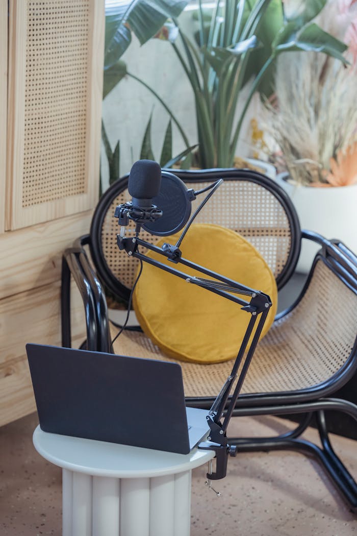 gallery-04 Modern laptop and microphone on tripod placed near wicker chair in modern studio before recording podcast